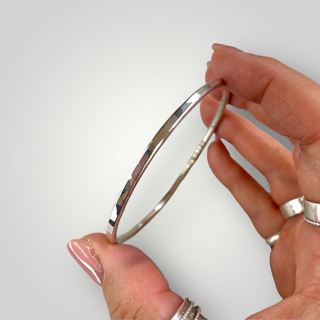 A solid sterling silver bangle with a hammered finish