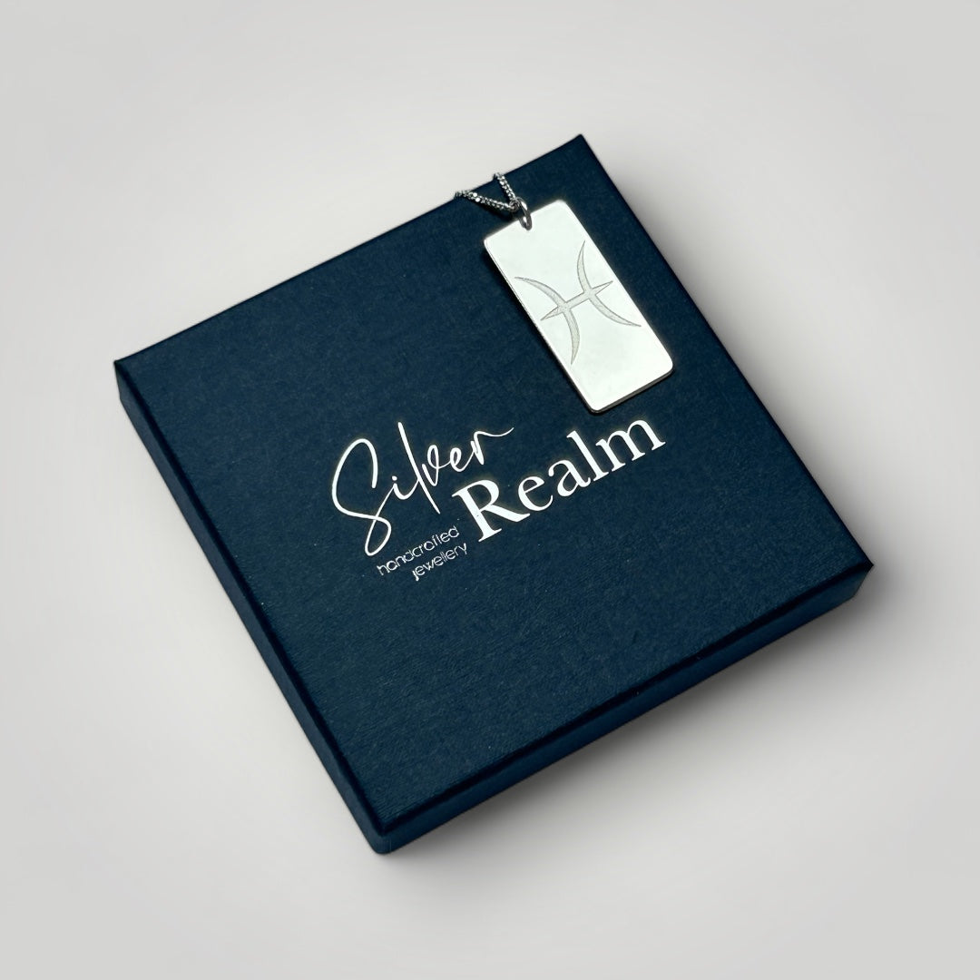 Sterling silver zodiac pendant necklace on top of a branded gift box.