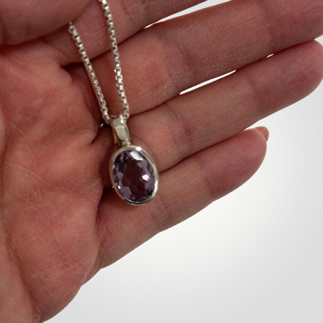 Close-up of oval faceted amethyst pendant handcrafted in sterling silver
