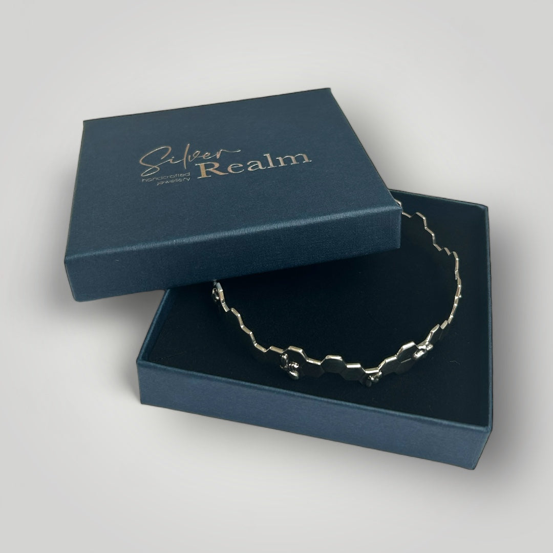 Silver bee bangle in an open blue box with 'Silver Realm' branding on a light gray background