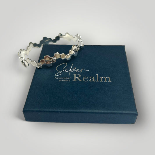 Silver Bee bangle on a 'Silver Realm' branded box