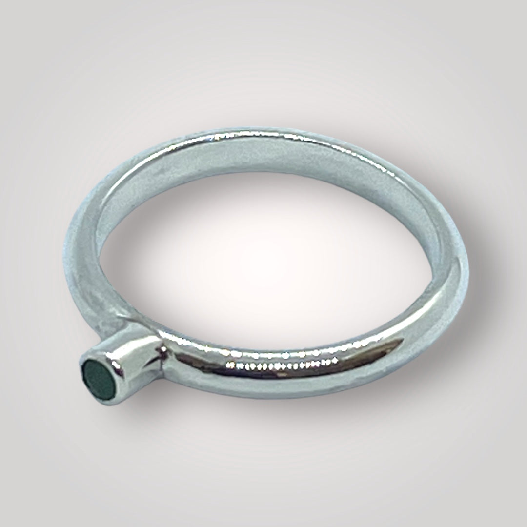 Emerald and sterling silver stacking ring on a light grey background
