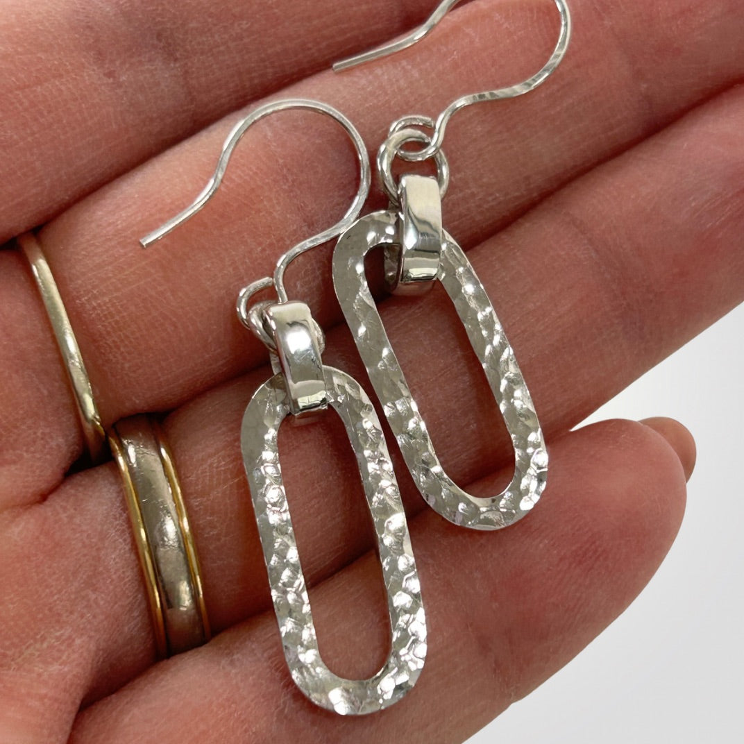 Close-up of hammered texture on handmade sterling silver long loop earrings