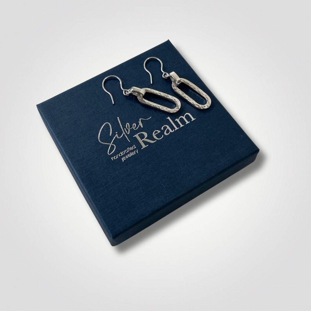 Hammered sterling silver long loop earrings displayed on a Silver Realm gift box