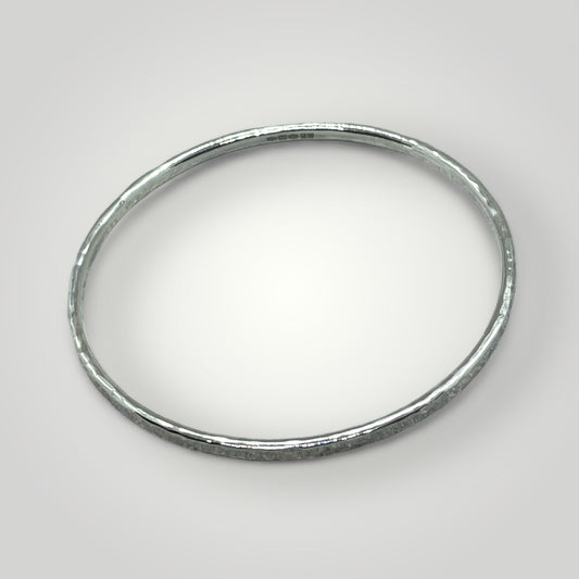 a hammered sterling silver bangle with the hallmark visible on a light grey background
