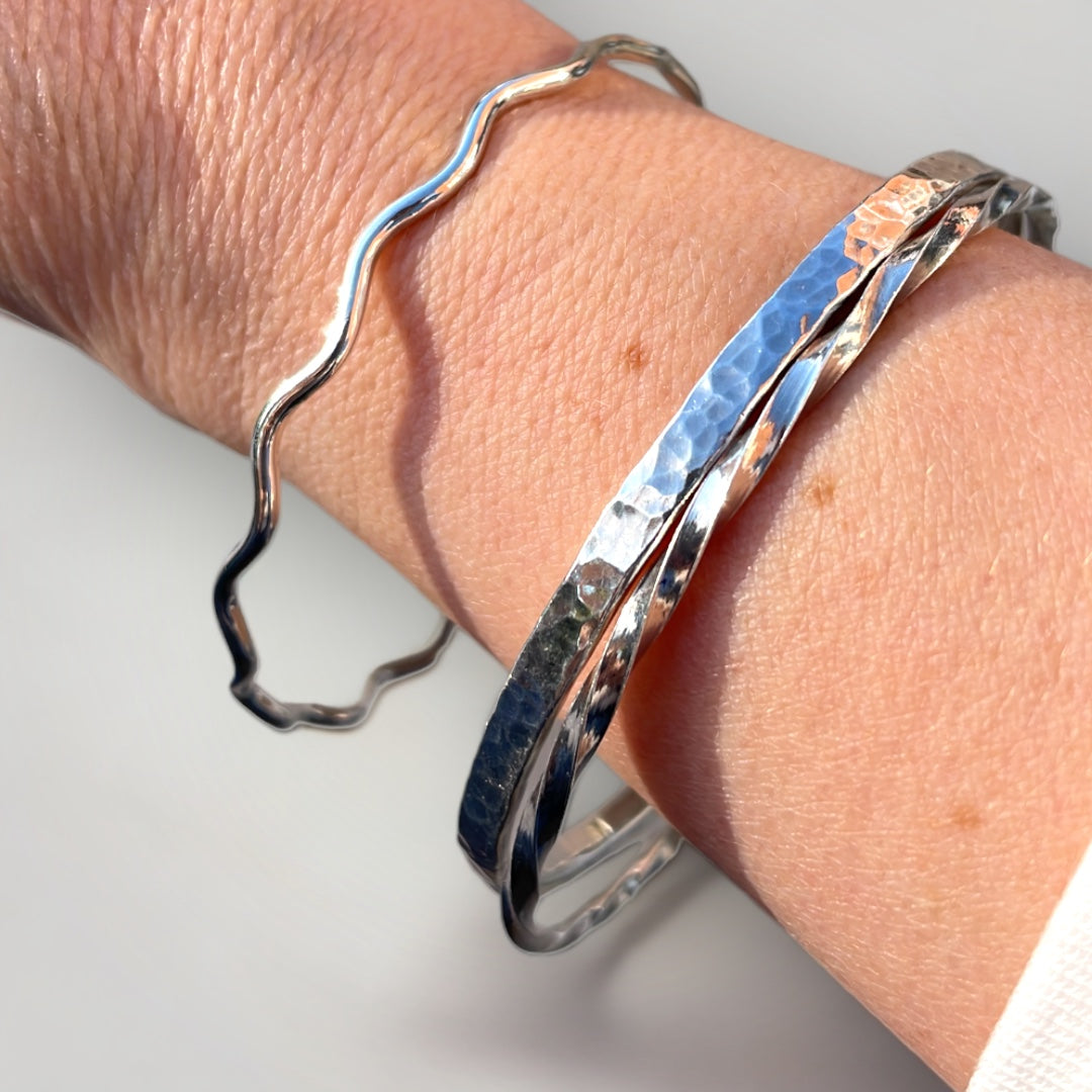 Three sterling silver bangles shown being worn on a wrist