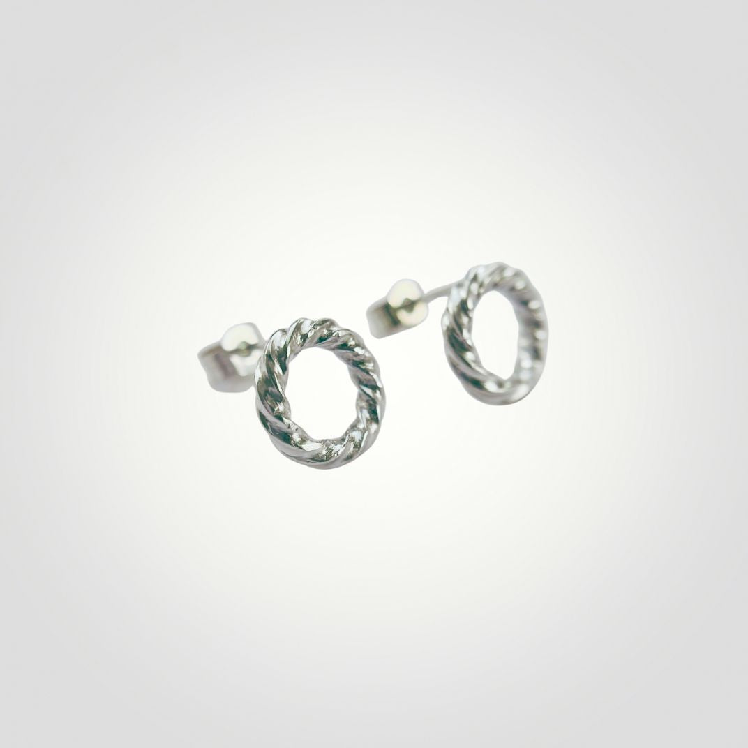 Close-up of handmade sterling silver stud earrings with twisted open circle design