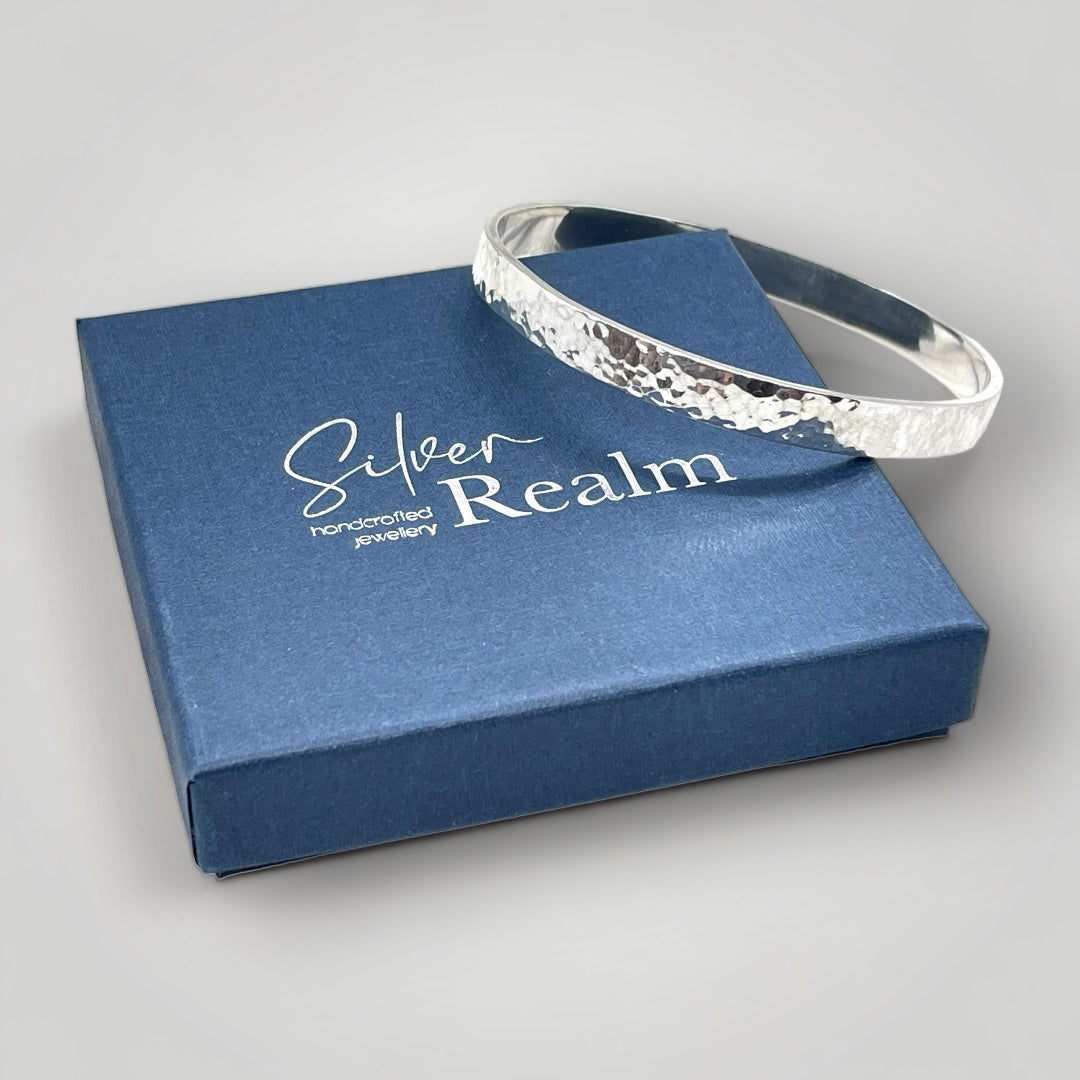 Hammered silver bangle on a 'Silver Realm' branded blue box
