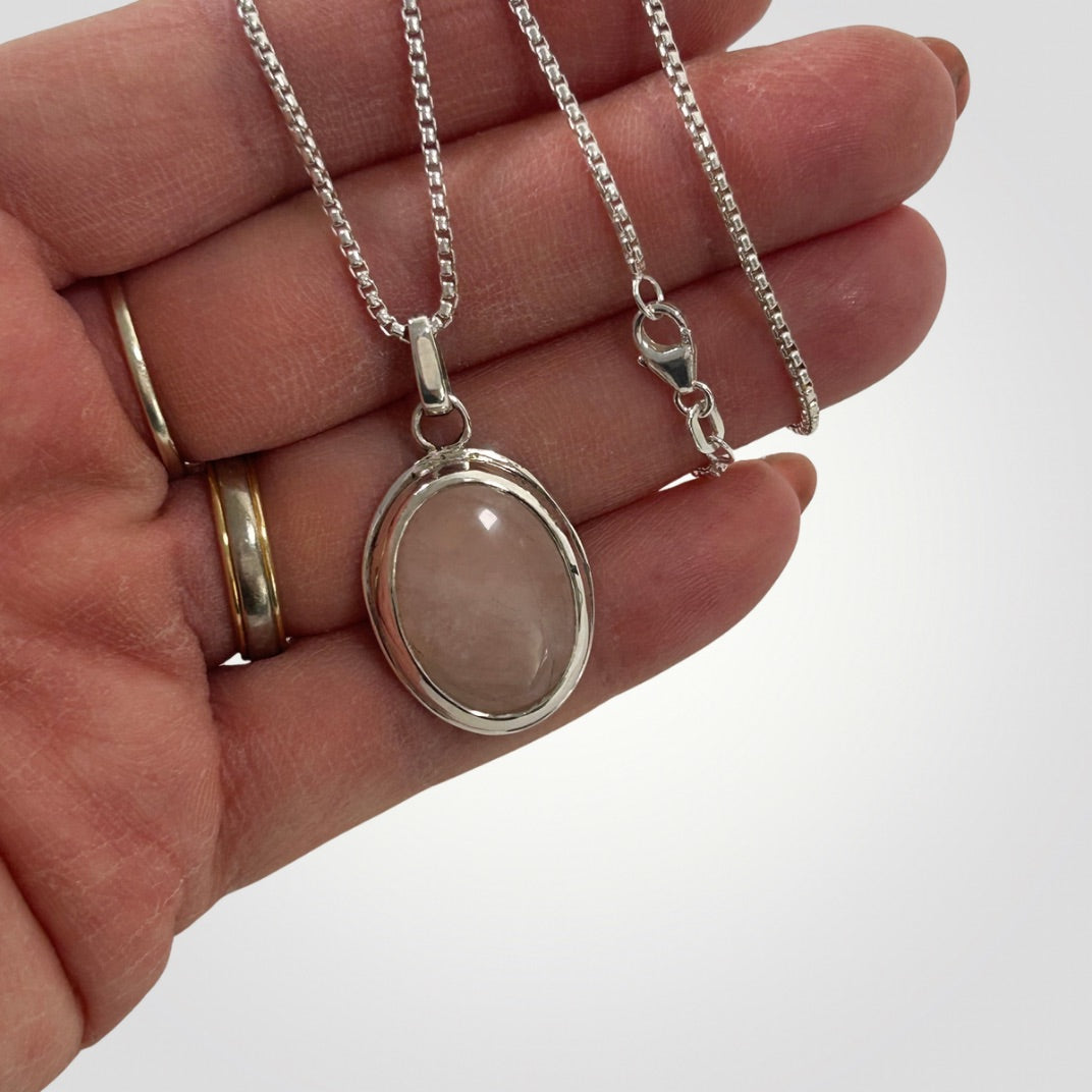 Rose quartz sterling silver pendant necklace in a hand
