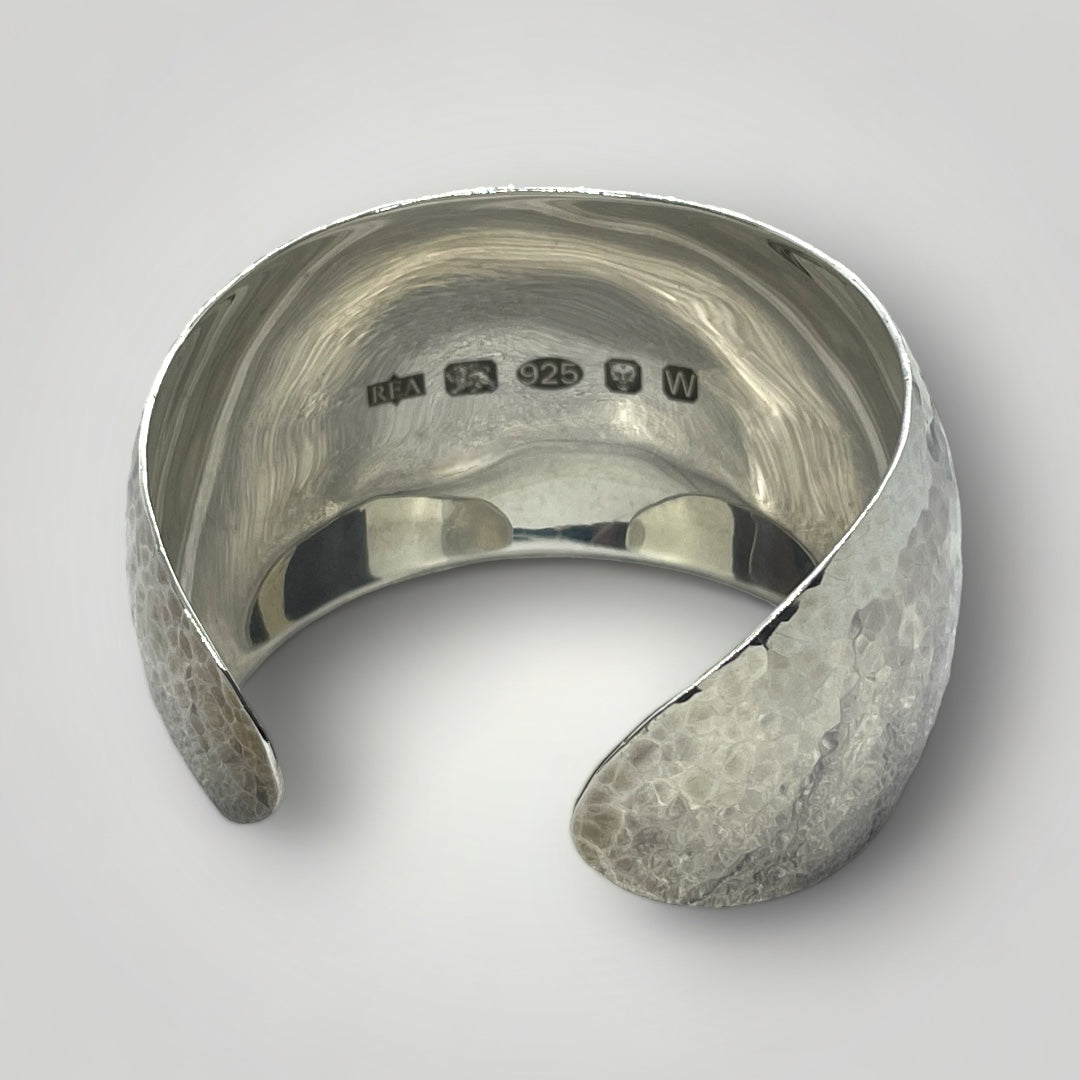Handmade wide Argentium silver cuff bangle with hammered exterior, mirror-polished interior, and large feature hallmark
