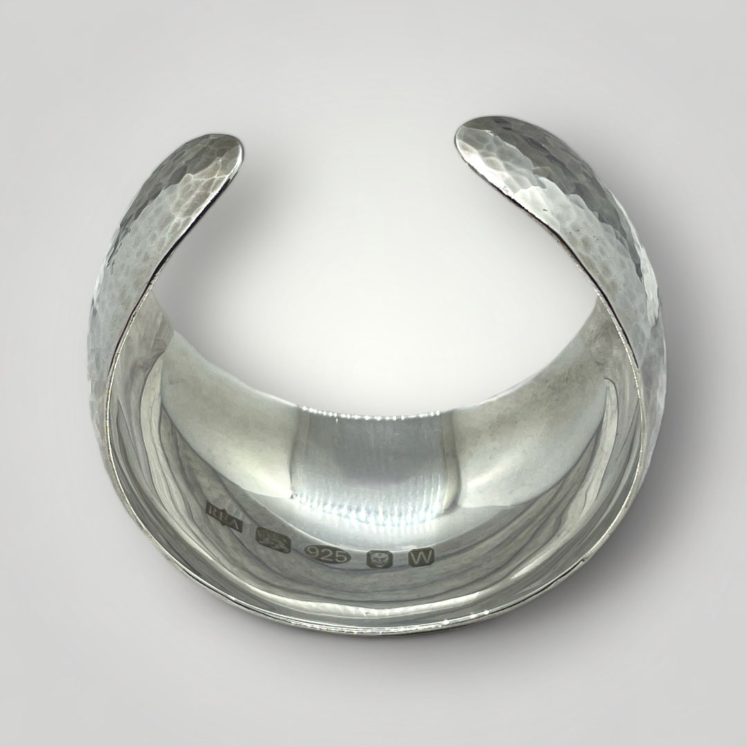 Handmade wide Argentium silver cuff bangle with hammered exterior, mirror-polished interior, and large feature hallmark
