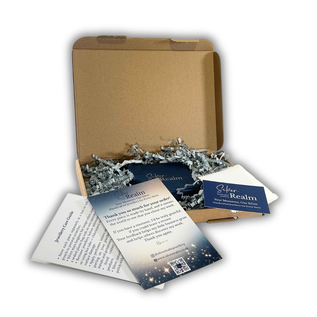 Open cardboard  box with Silver Realm Jewellery branded gift box and packing  materials on a white background