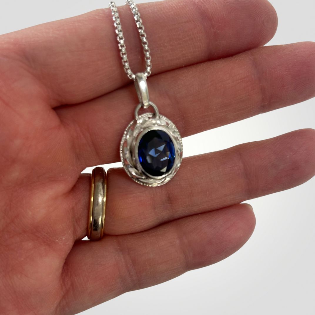 Synthetic sapphire pendant shown in hand for scale