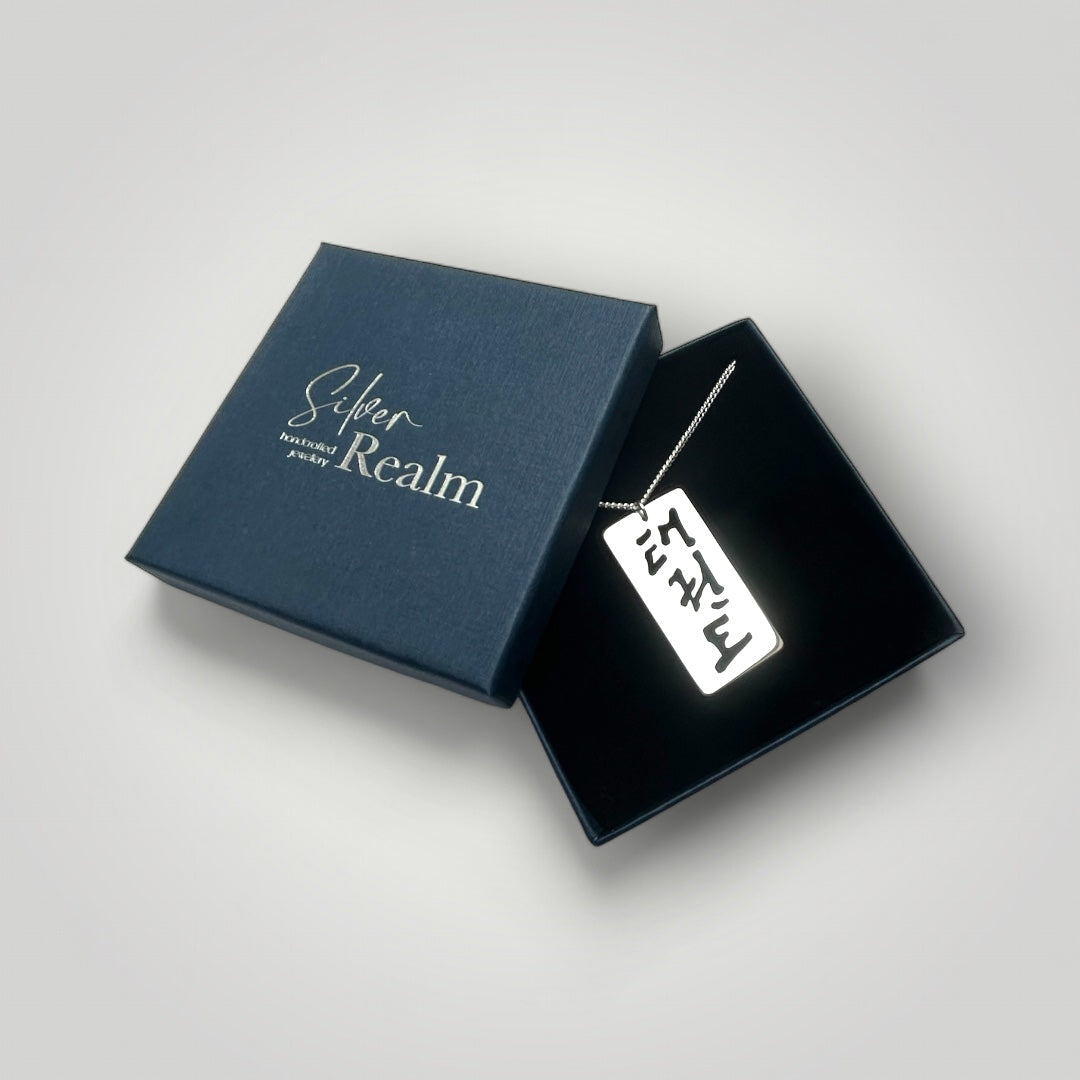 Sterling silver pendant with cut-out characters reading Taekwon-Do in Korean script in an open, Silver Realm Jewellery gift box on a gray background