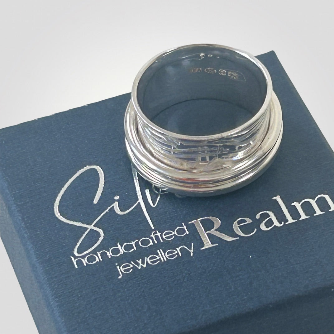 UK hallmark inside handmade sterling silver double spinner ring sitting on top of a blue, branded gift box