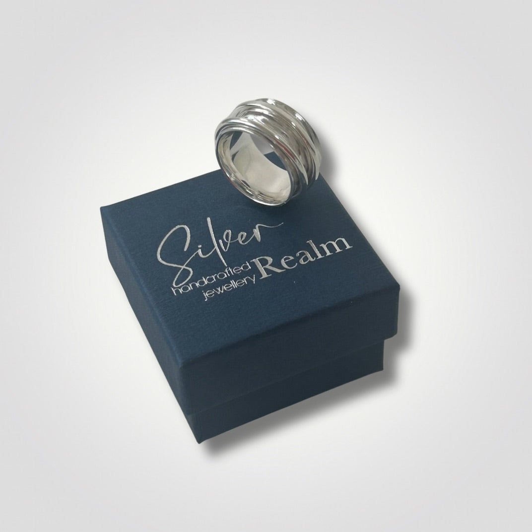 Wide textured sterling silver double spinner ring sitting on top of a Silver Realm gift box