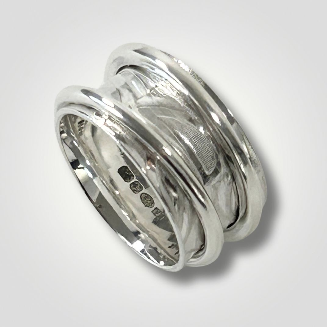 Wide textured sterling silver double spinner ring on a light grey background