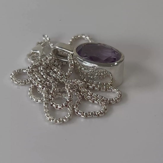 Faceted amethyst sterling silver pendant necklace on an 18 inch box chain
rotating on a light grey background
