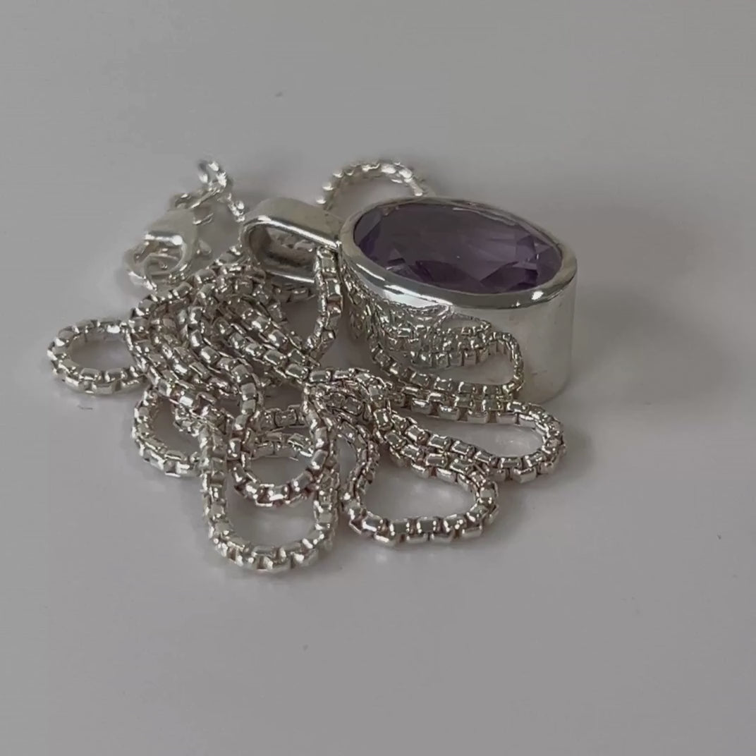 Faceted amethyst sterling silver pendant necklace on an 18 inch box chain
rotating on a light grey background
