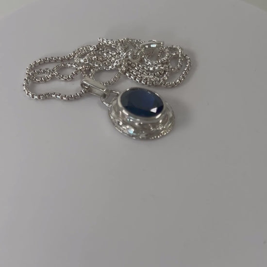 Synthetic sapphire and sterling silver pendant rotating on a light grey background

