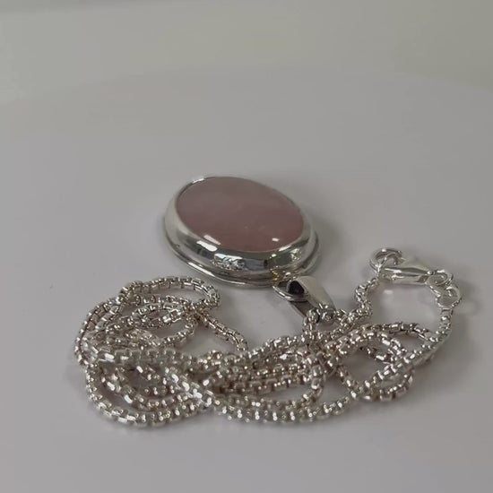 Rose quartz sterling silver pendant necklace rotating on a light grey background
