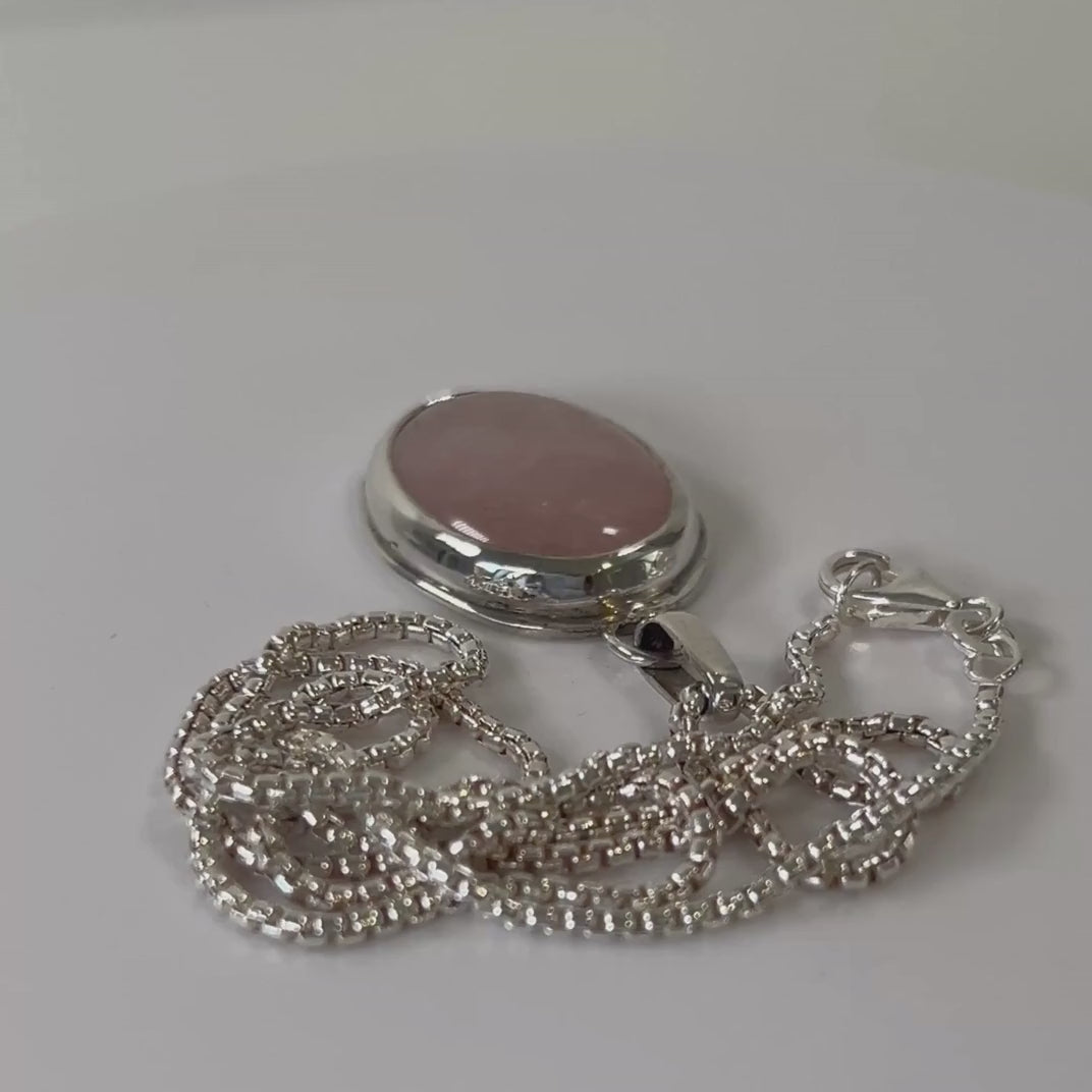 Rose quartz sterling silver pendant necklace rotating on a light grey background
