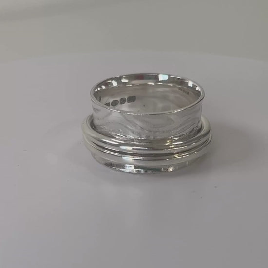 Wide textured sterling silver double spinner ring rotating on a light grey background
